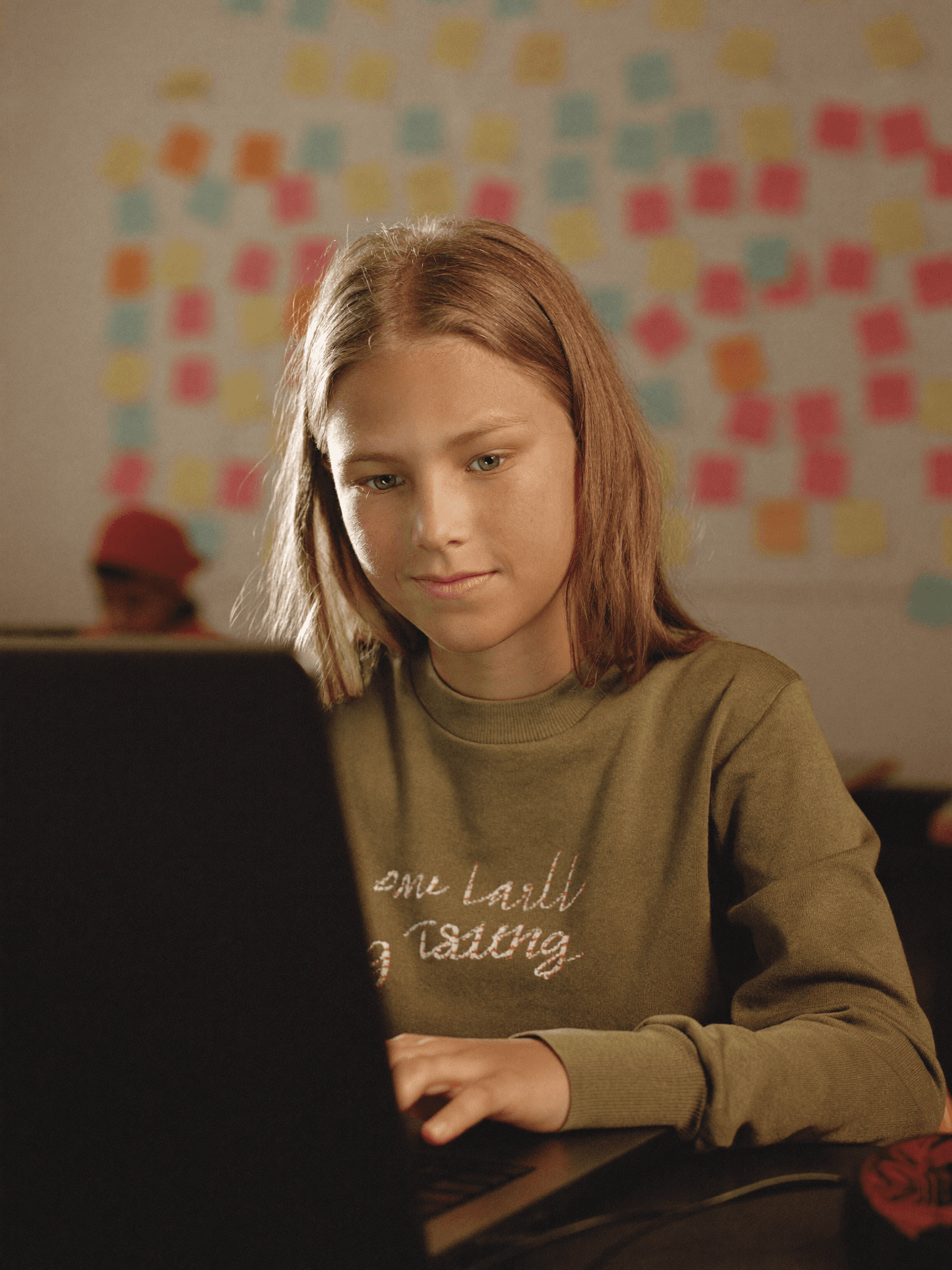 A focused young girl writing code on a laptop
